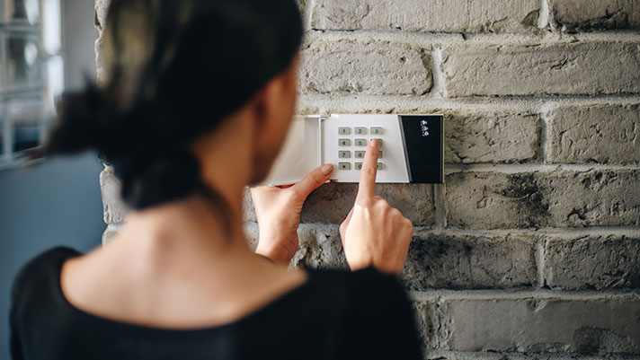 woman entering code in home alarm system